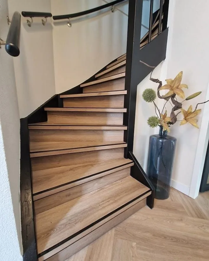 Gerenoveerde trap met houten treden en zwarte neuzen, naast een pvc-vloer